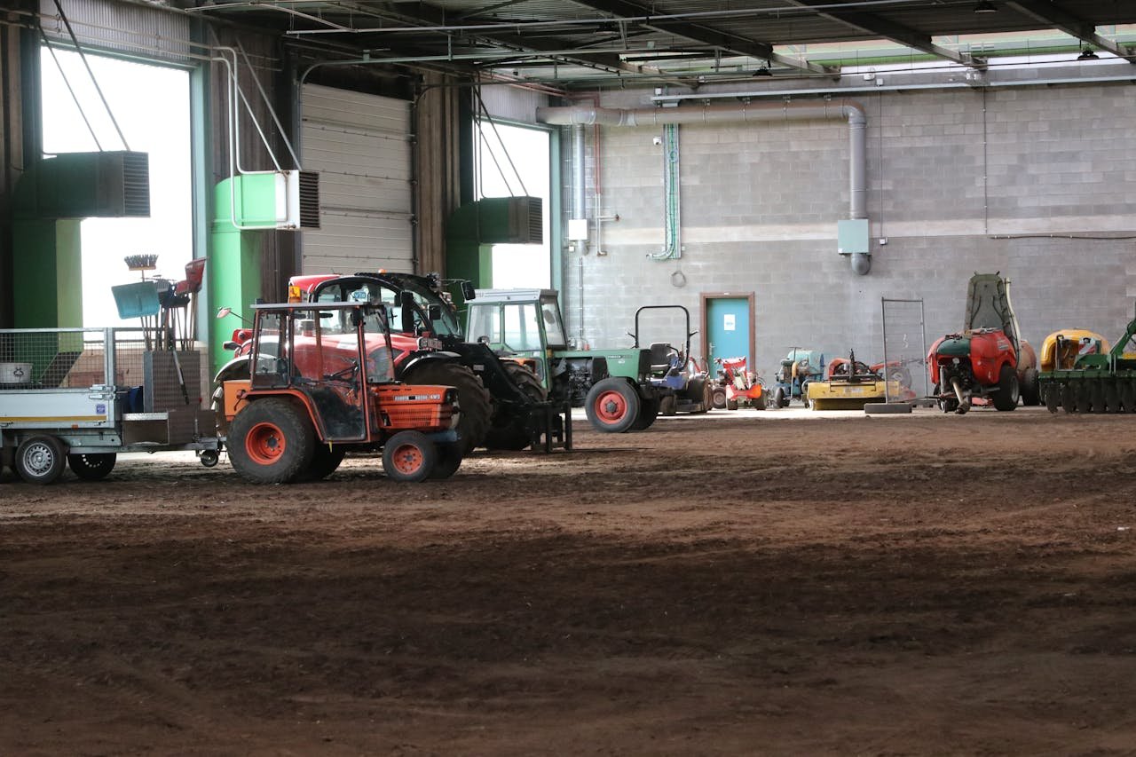 Image of various tractors and farm machinery stored in a large indoor facility.